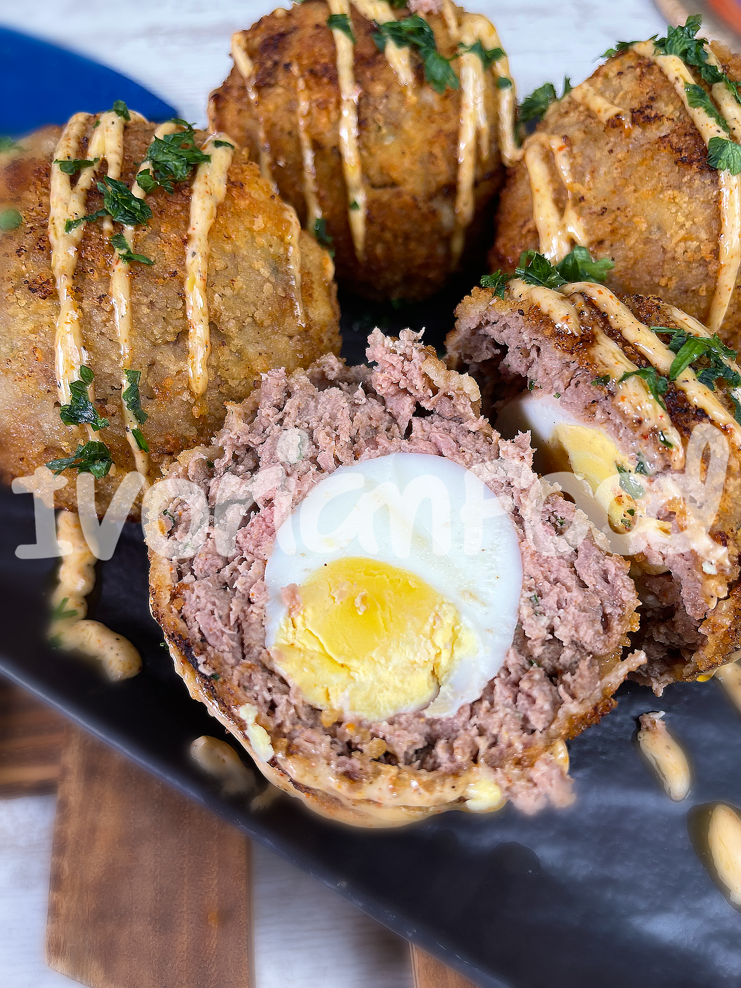 Pour les Boulettes surprises, on enrobe des œufs cuits de chair à saucisse, on les pane avec de la farine, de l'œuf battu et de la chapelure, puis on les fait frire.